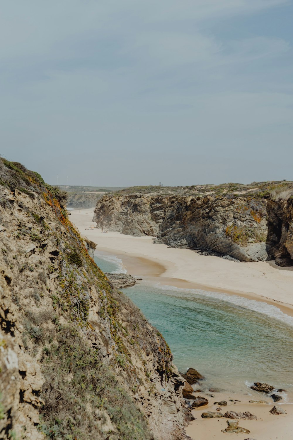 a beach with a cliff and water