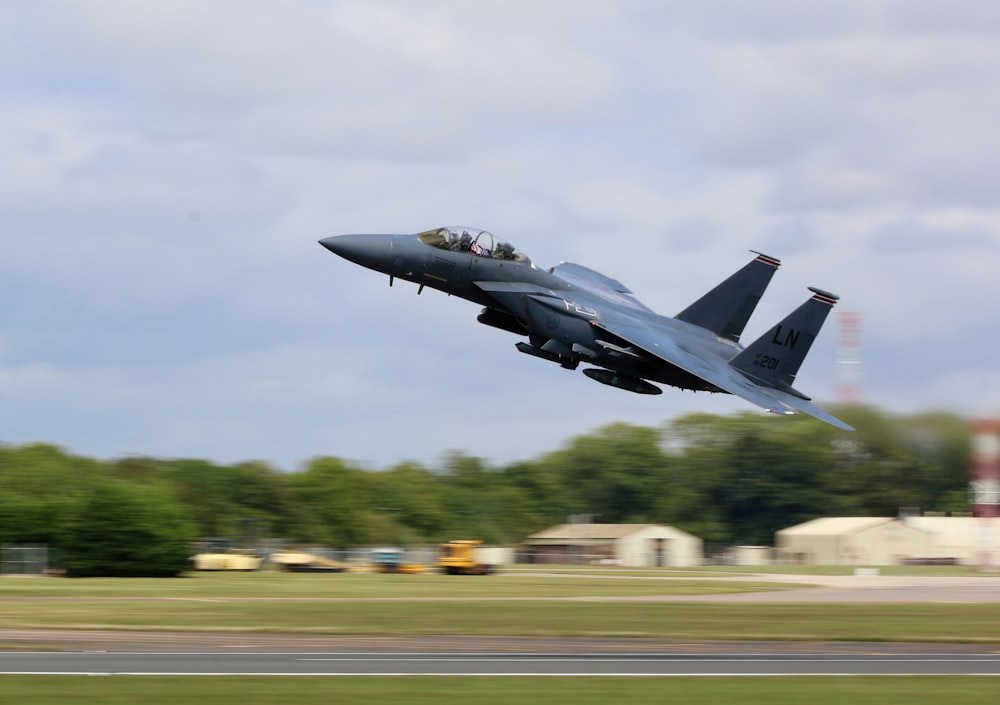 a fighter jet flying over a runway