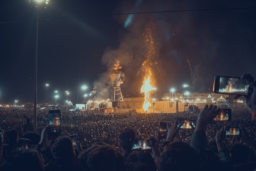 a large crowd of people watching a stage with a large fire