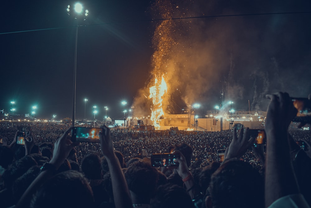 Eine Menschenmenge beobachtet eine Bühne mit Feuerwerk im Hintergrund