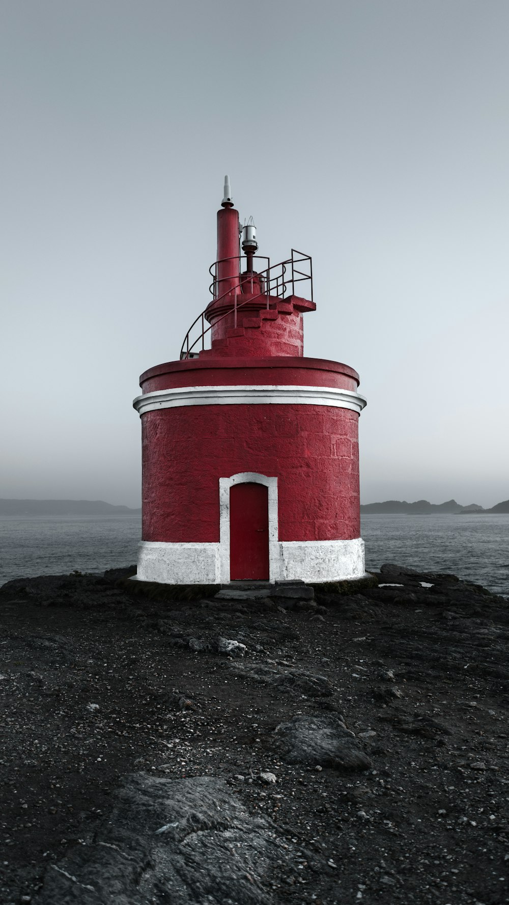 a red and white lighthouse on a rocky shore