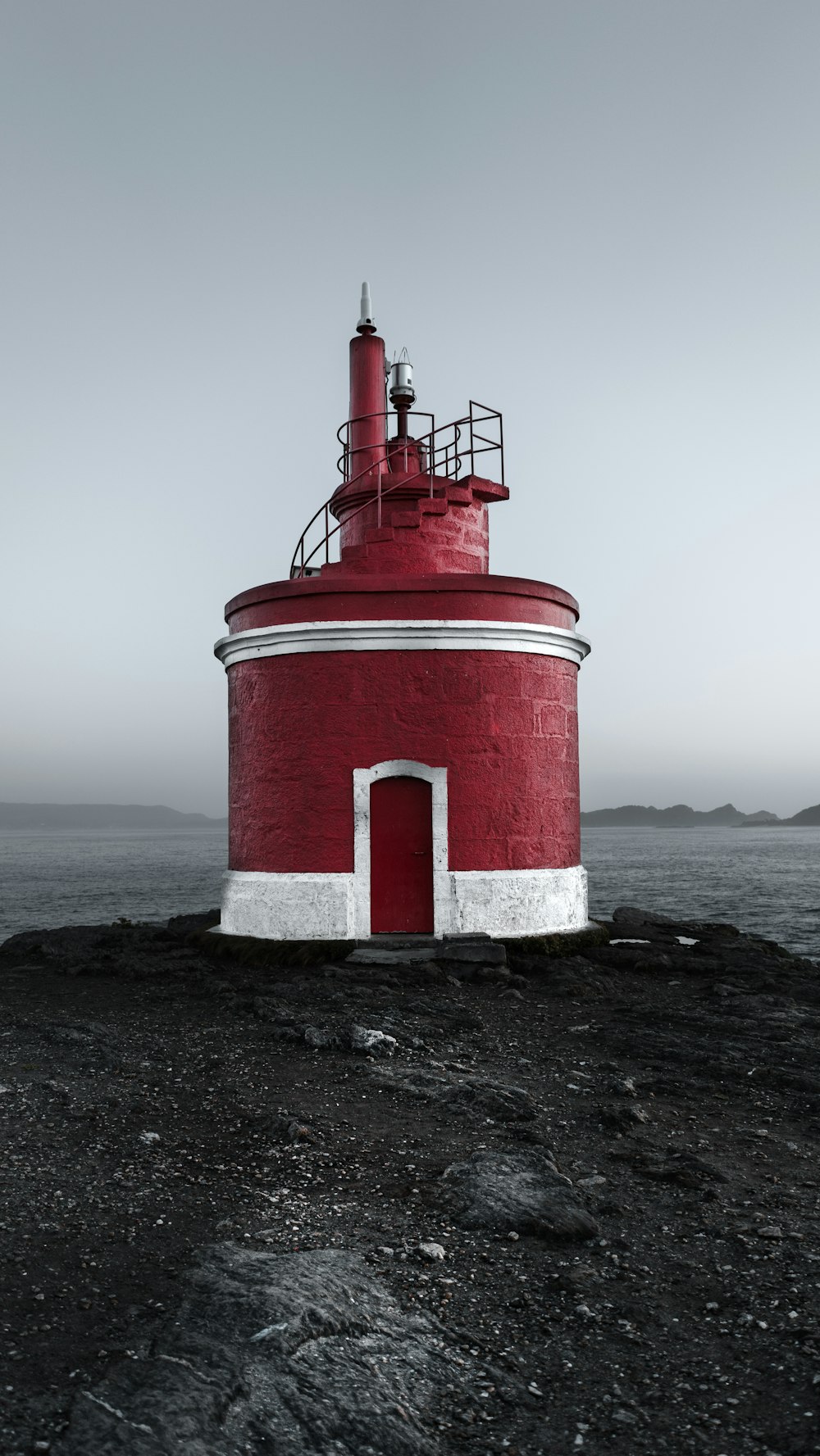 Ein rot-weißer Leuchtturm an einem felsigen Ufer