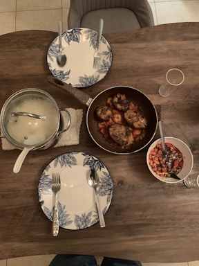Cozy home kitchen table set with creamy chicken, fresh salad, roasted veggies, and dessert plates.