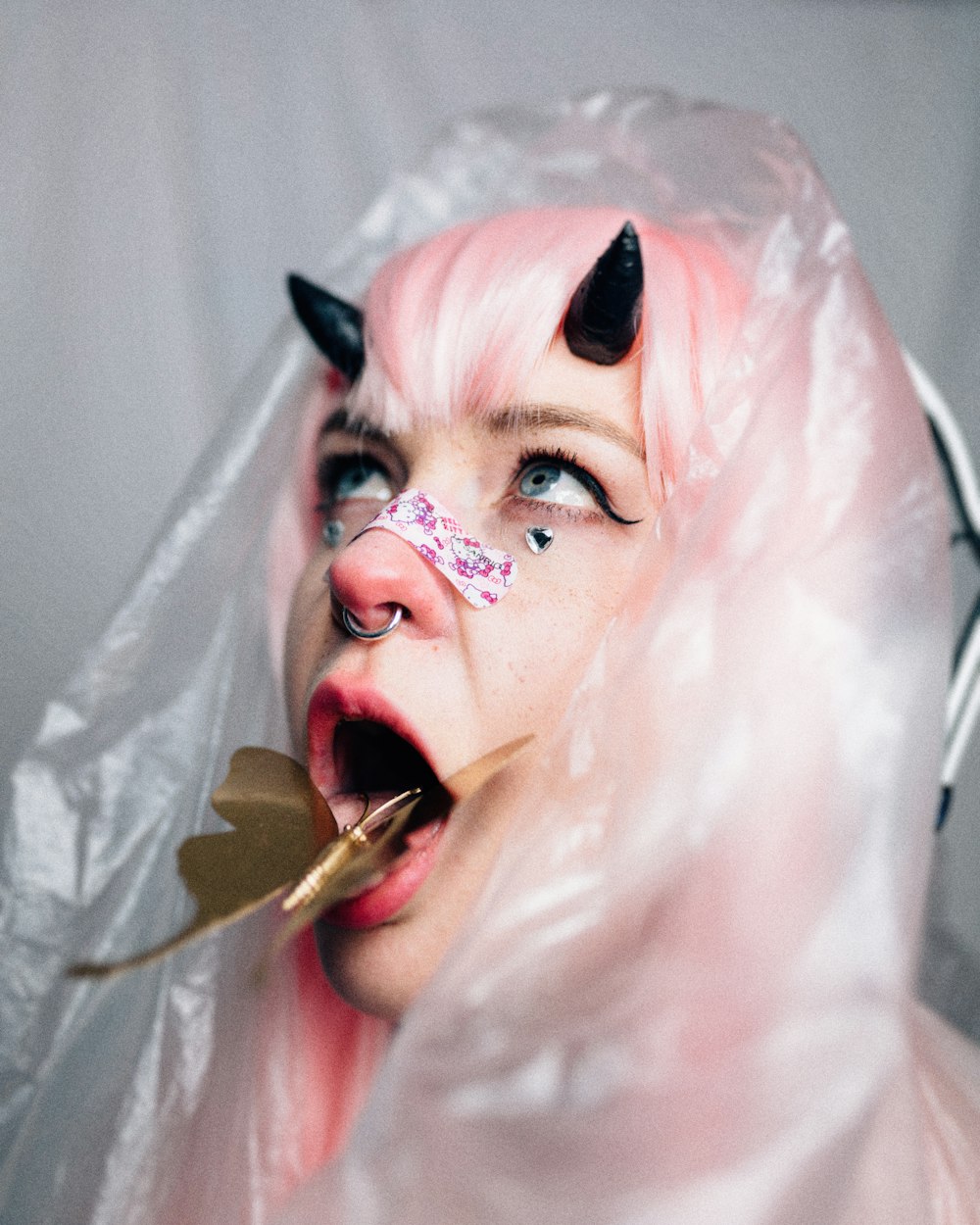 a person with a pink wig and a white mask with a cigarette in the mouth