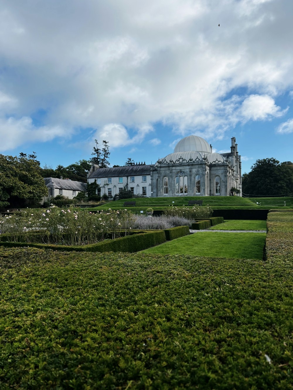 a large white building with a dome and a garden in front of it