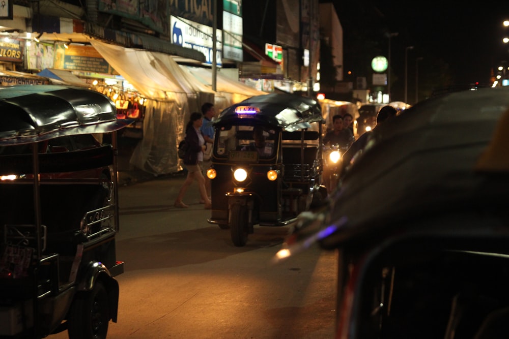 a group of people walking down a sidewalk next to a row of cars