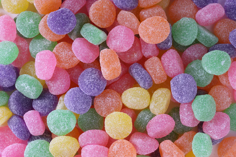 Assorted CBD gummies in pastel colors on a neutral background