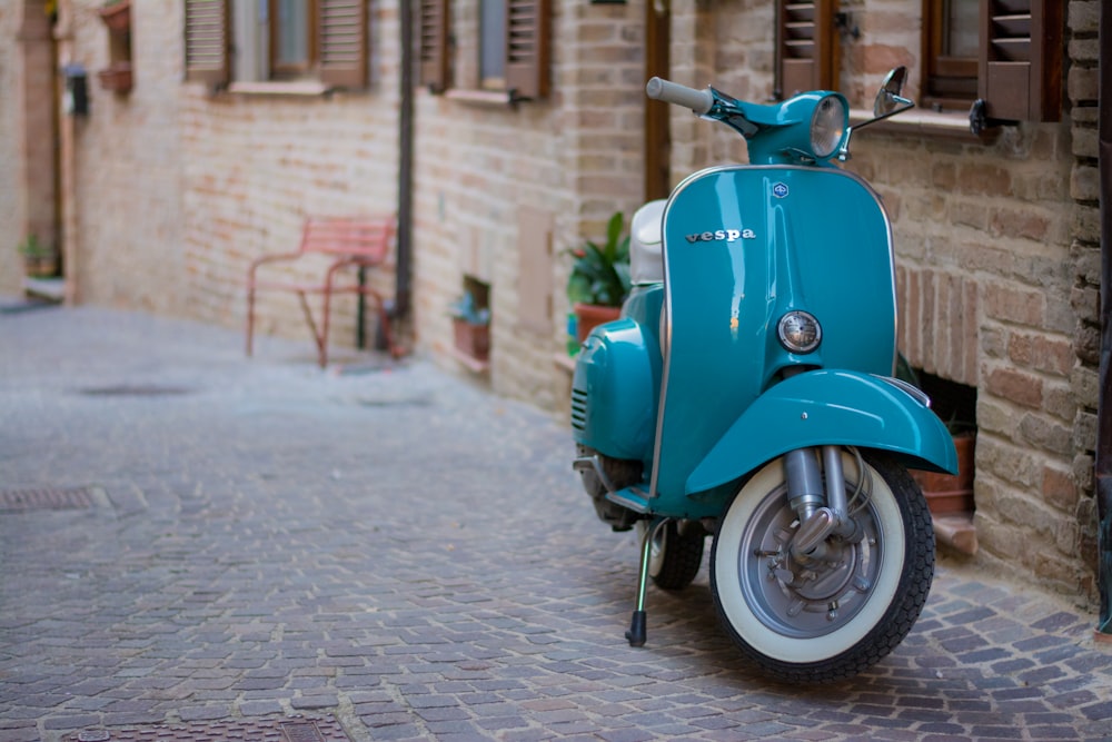 a blue scooter parked on a cobblestone street