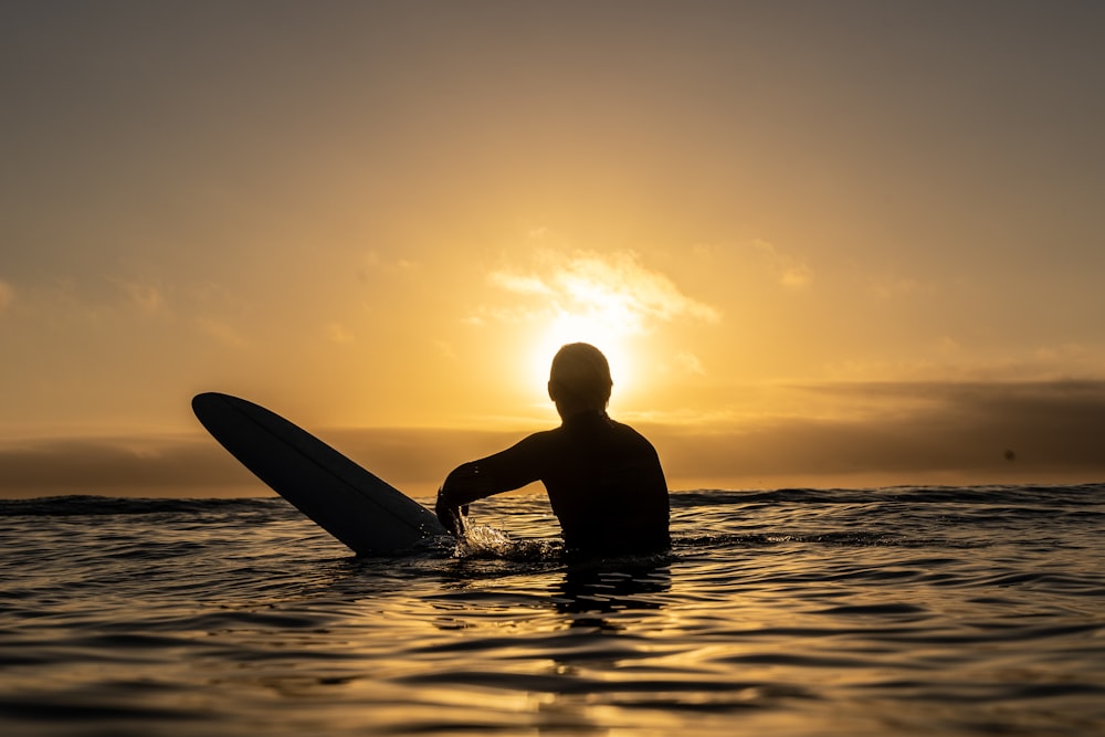 a person sitting in the water with a surfboard