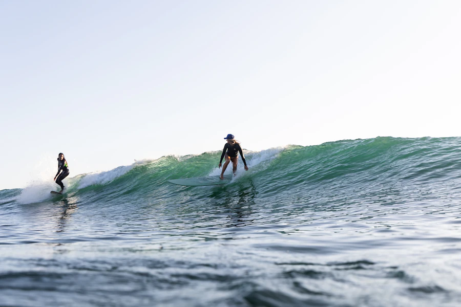 Two friends sharing a surfboard on an ocean wave