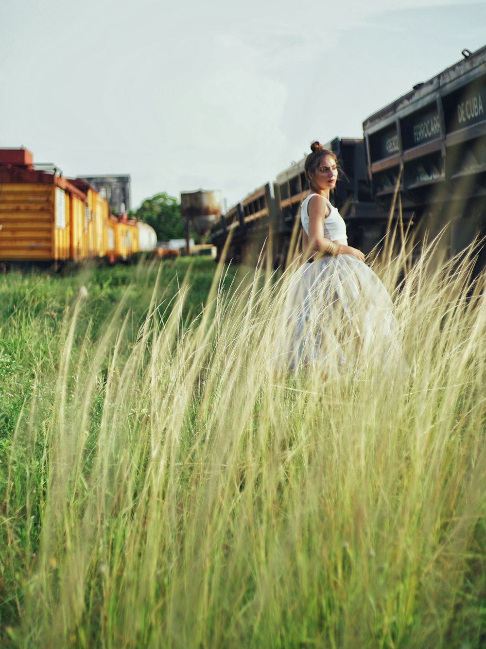 a man standing in a field of tall grass with a train in the background