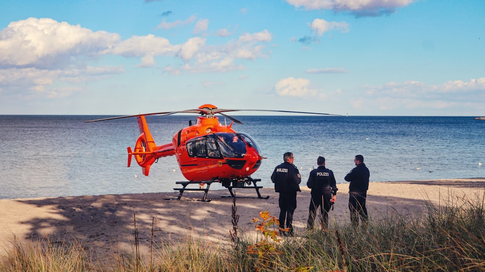 a group of people standing next to a helicopter on a dirt road by water