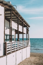 a white building with a beach and blue water in the background