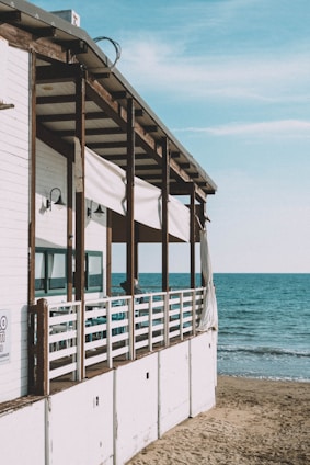 a white building with a beach and blue water in the background
