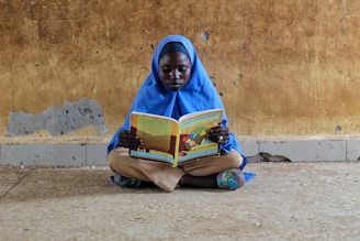 a person sitting on the ground reading a book