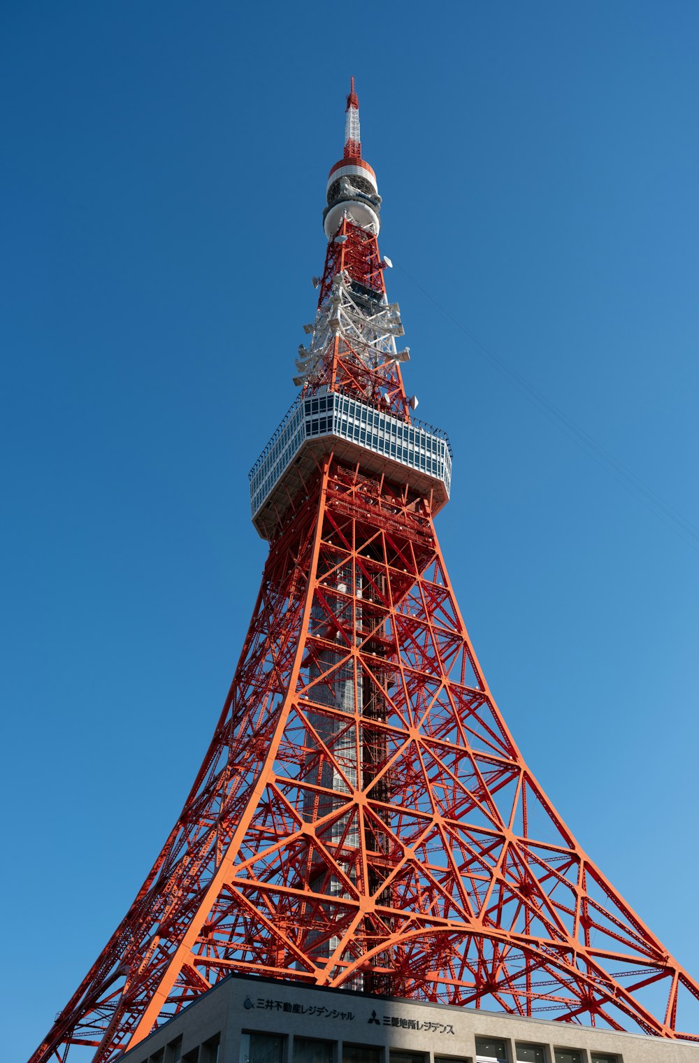 una alta torre de metal con la Torre de Tokio al fondo