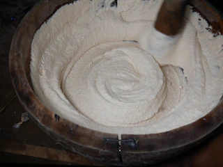 A close-up of creamy shea butter whipped into a light, fluffy texture in a rustic wooden bowl.