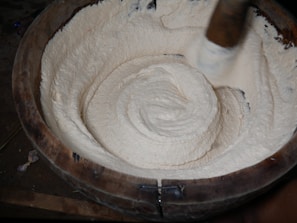 Close-up of Shea butter being hand-processed in a traditional wooden bowl.