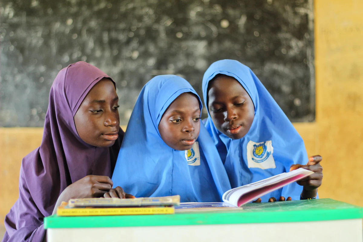 Students in school uniform reading a book together at a desk
