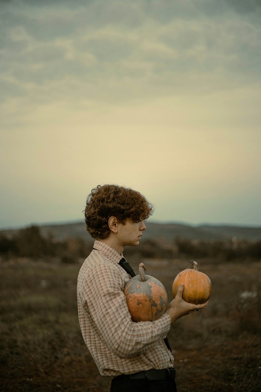 a boy holding two pumpkins