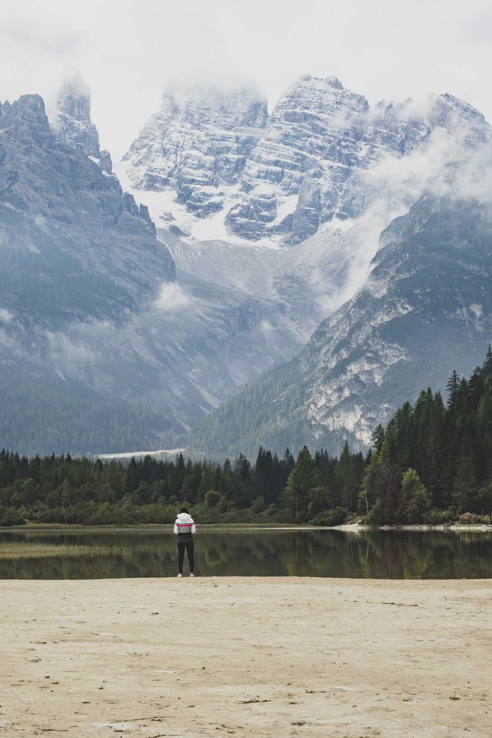 a person standing next to a lake with mountains in the background