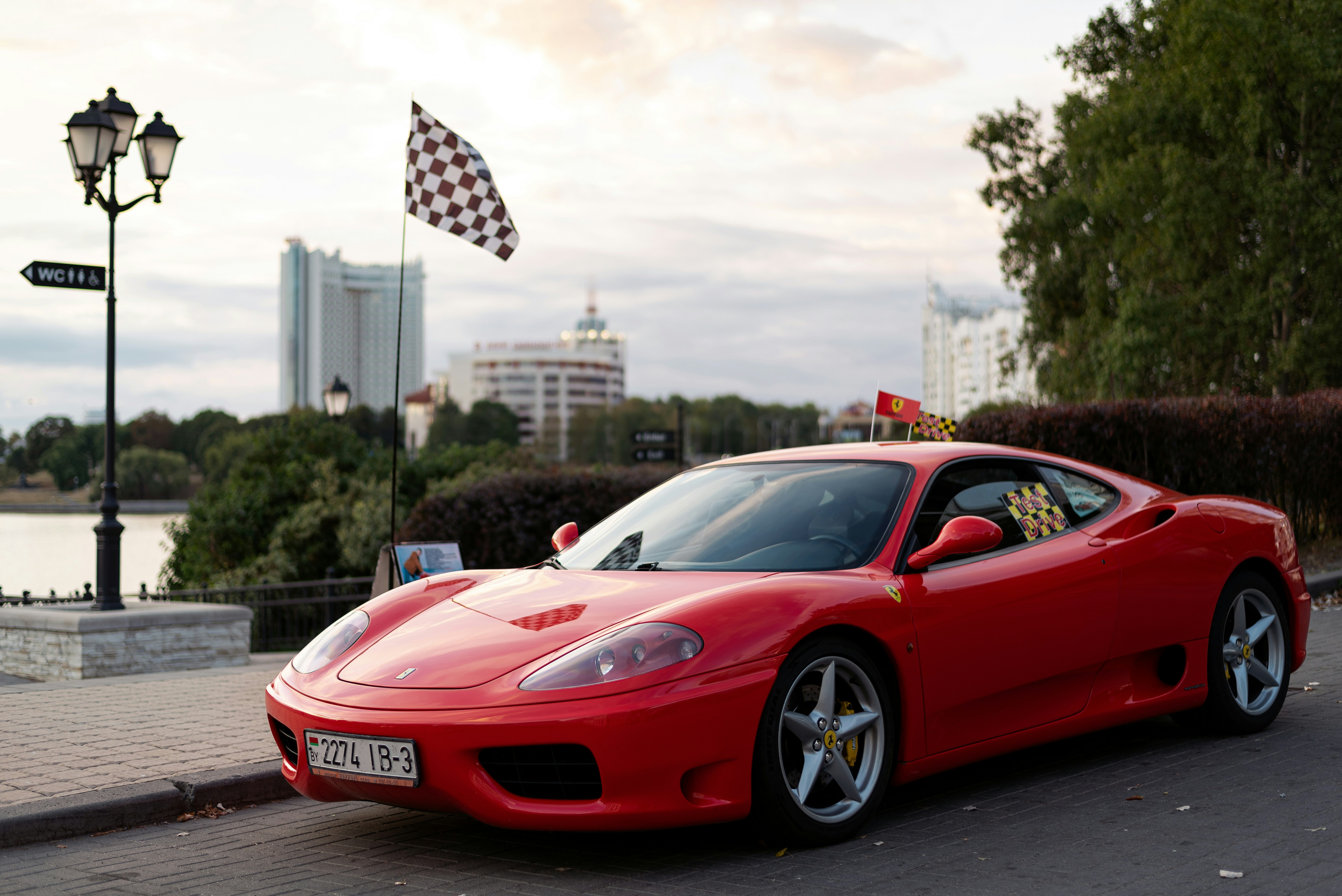 a red sports car parked on a street with a flag on a pole