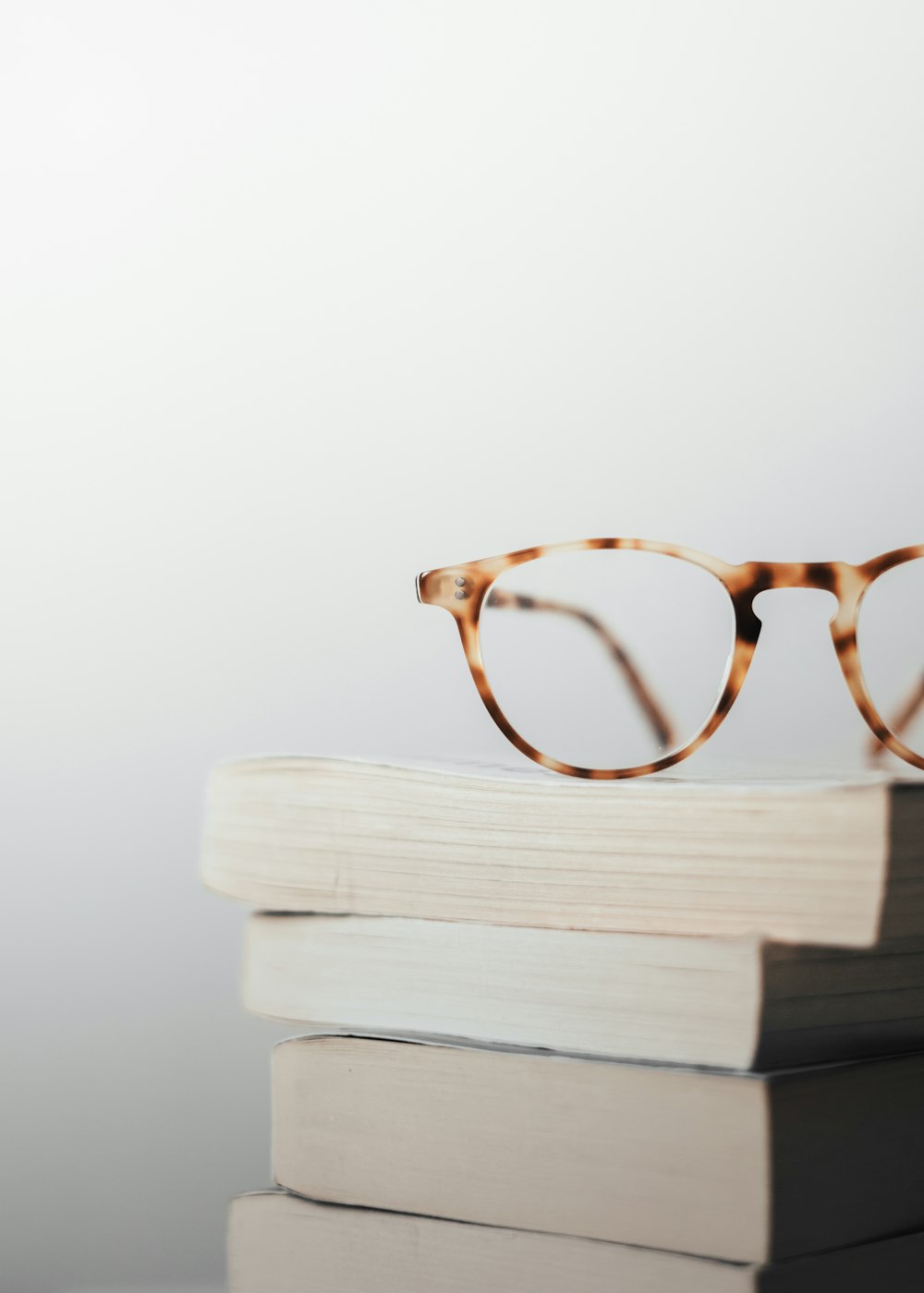a pair of glasses on top of a stack of books