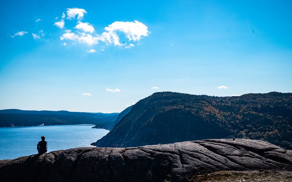 a person sitting on a rock looking at the water