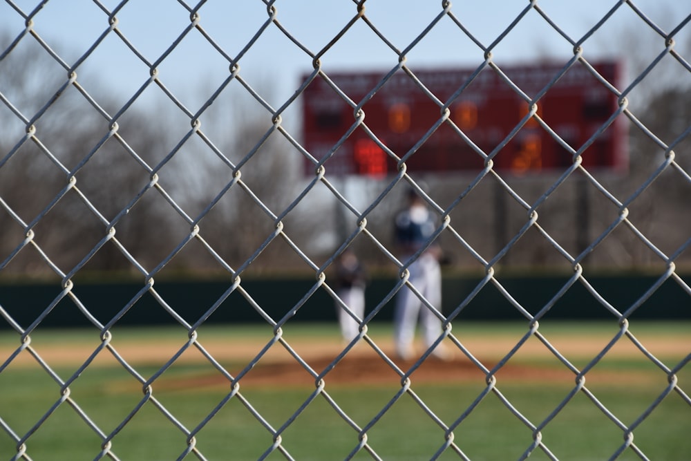 a baseball player behind a chain link fence