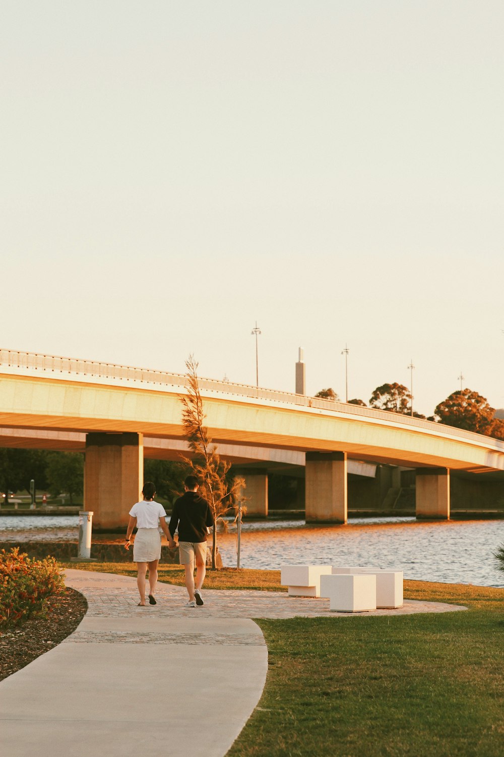 um casal de pessoas andando em um caminho por um edifício com uma ponte