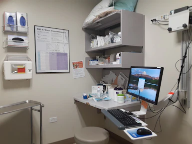 A focused medical assistant reviewing patient files on a computer screen in a bright office.