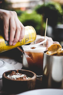 a person pouring a drink into a glass