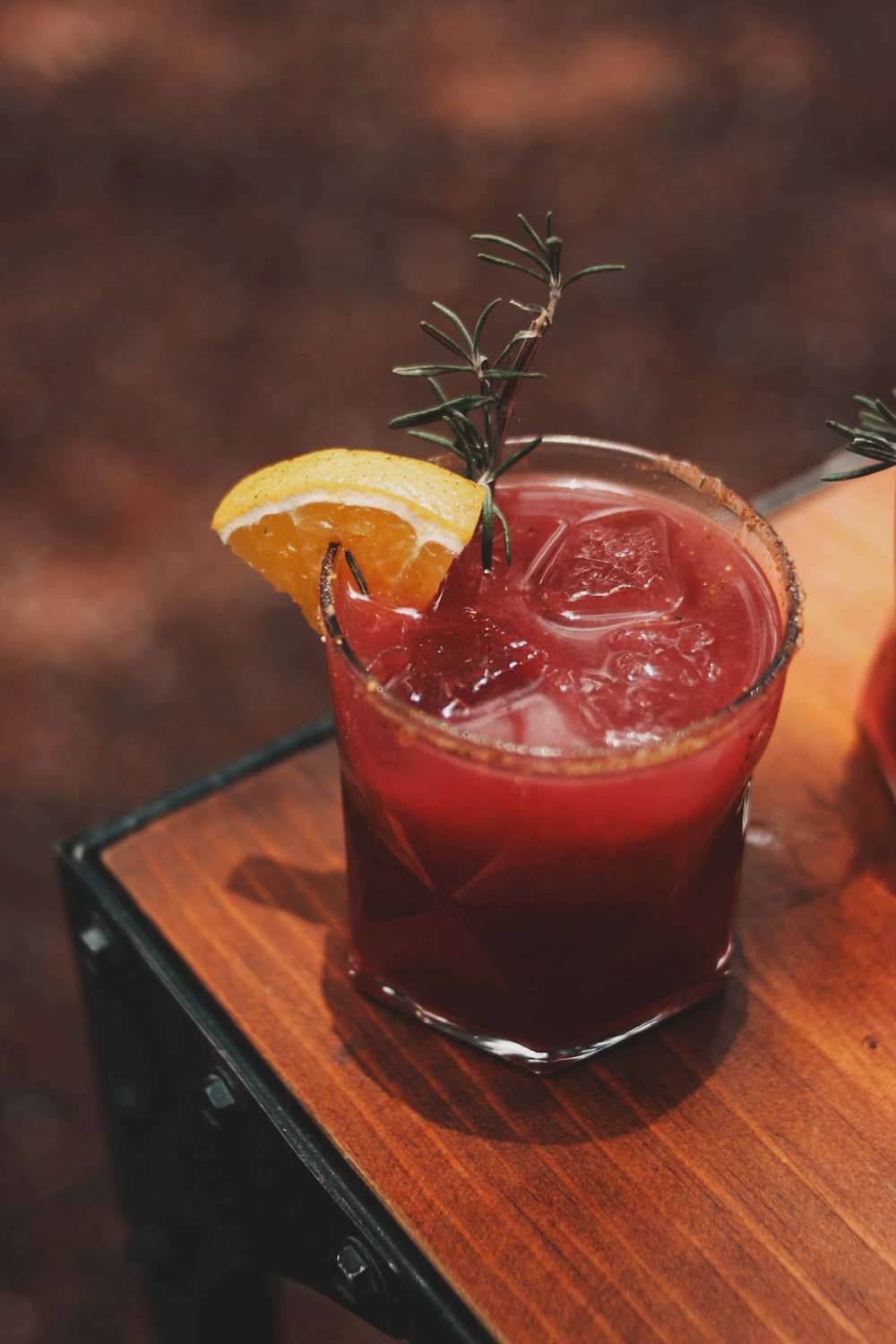 a glass of red liquid with a lemon wedge on top