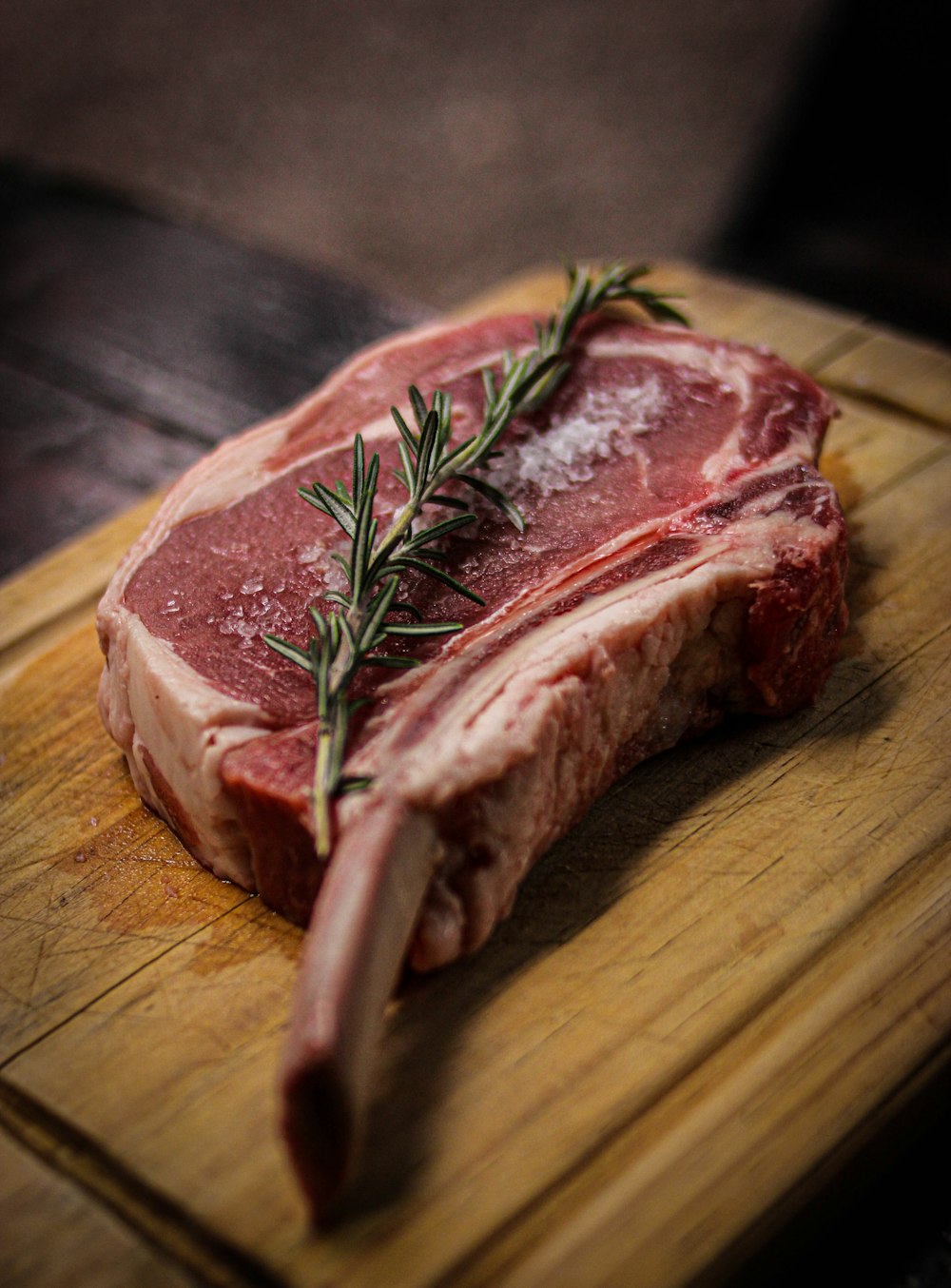 un morceau de viande crue avec une feuille verte sur une surface en bois