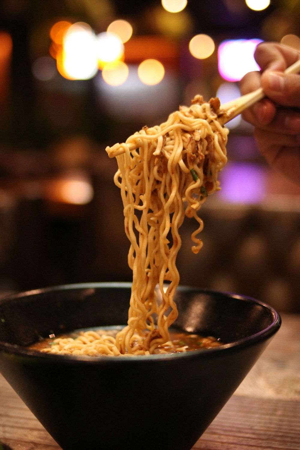 a hand holding a stick over a bowl of food