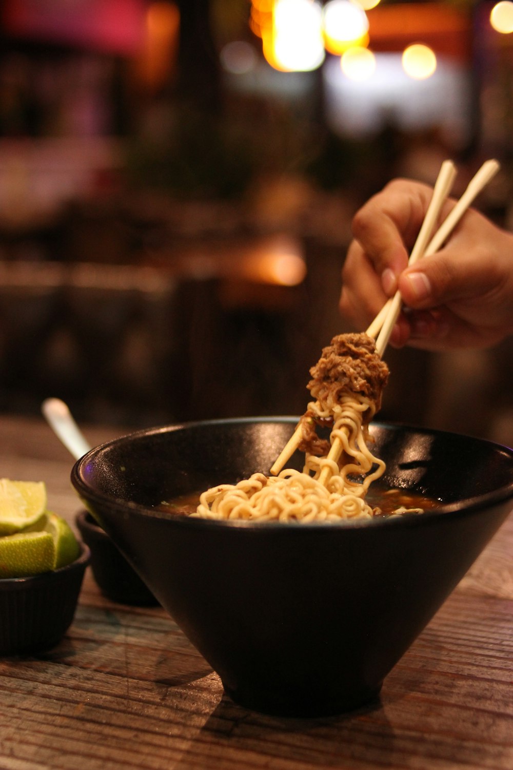 a hand holding chopsticks over a bowl of food
