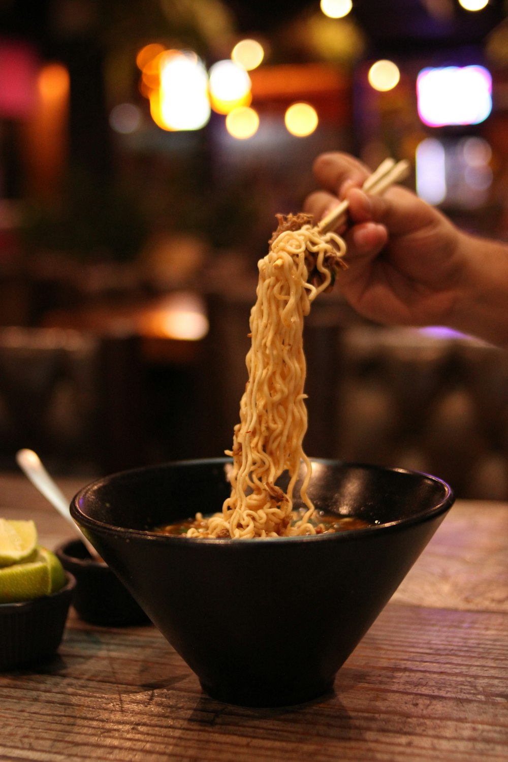 a hand holding a spoon over a bowl of food