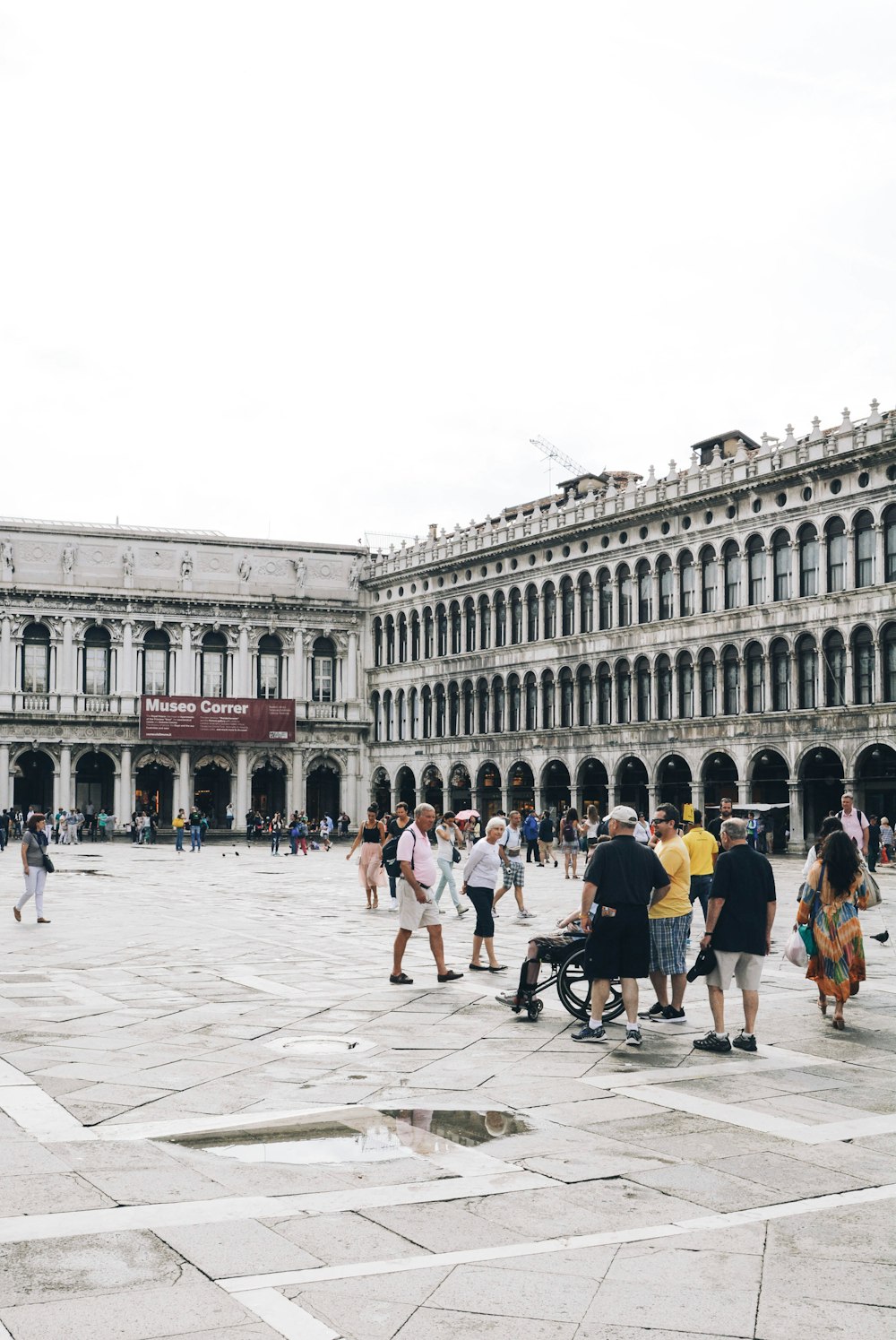 a group of people walking in a plaza in front of a building