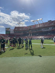 Outdoor sports event with students cheering on the field under a clear blue sky.