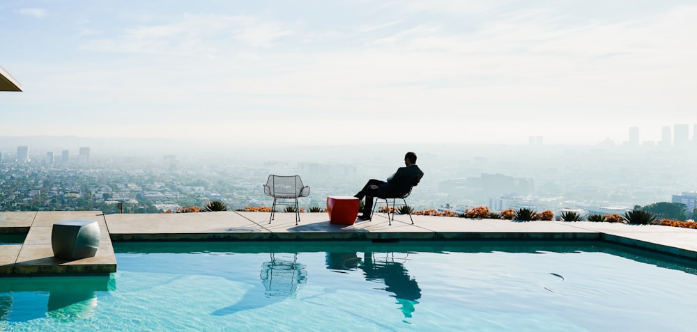 a person sitting in a chair by a pool
