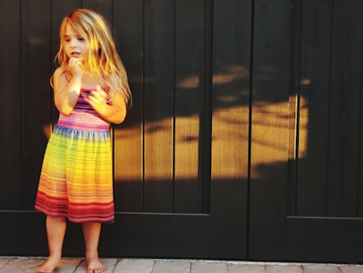 a girl standing in front of a black door