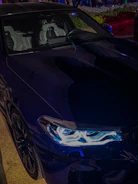 An expansive, moody shot of a sleek, black luxury car interior illuminated by subtle ambient lighting.