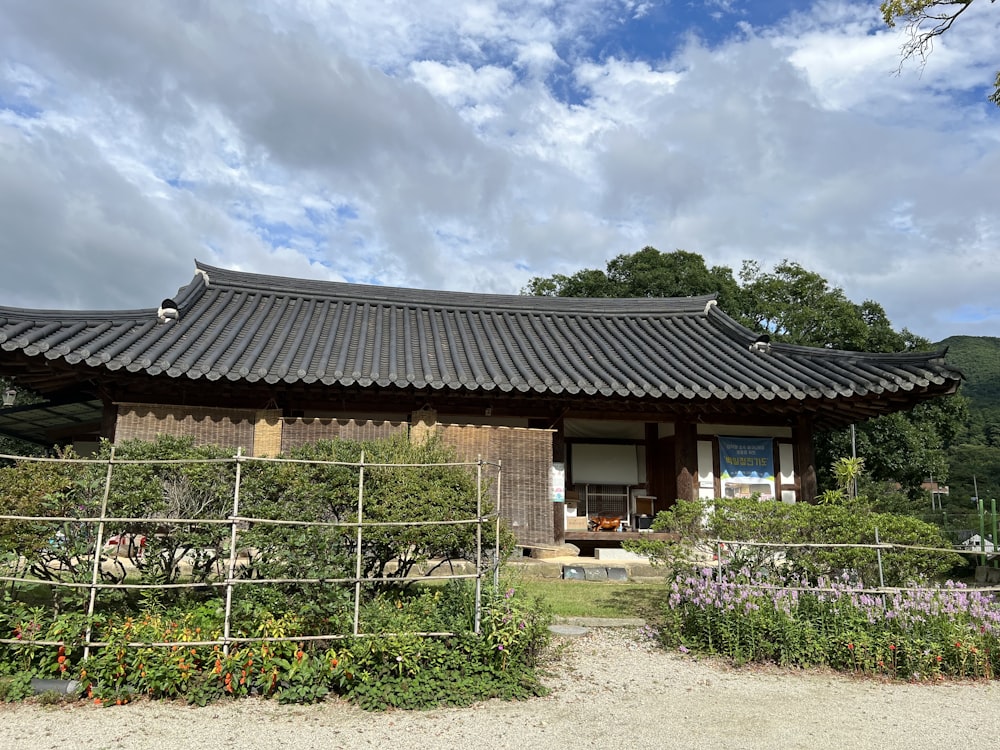 a house with a fence and flowers in front of it