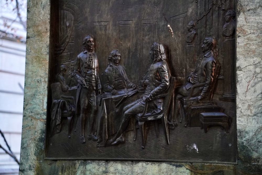 a stone sculpture of a group of people sitting on a bench