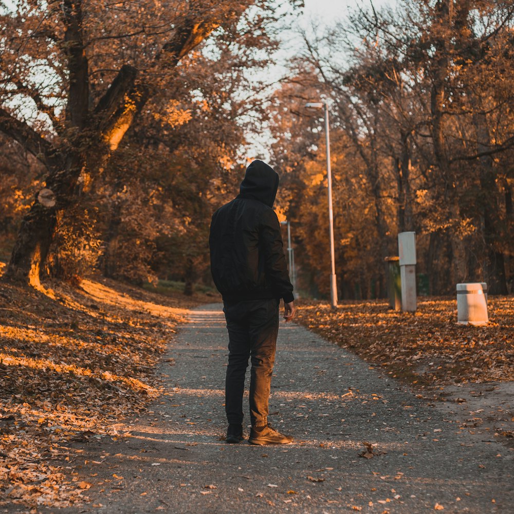 a person walking on a road with leaves on the ground