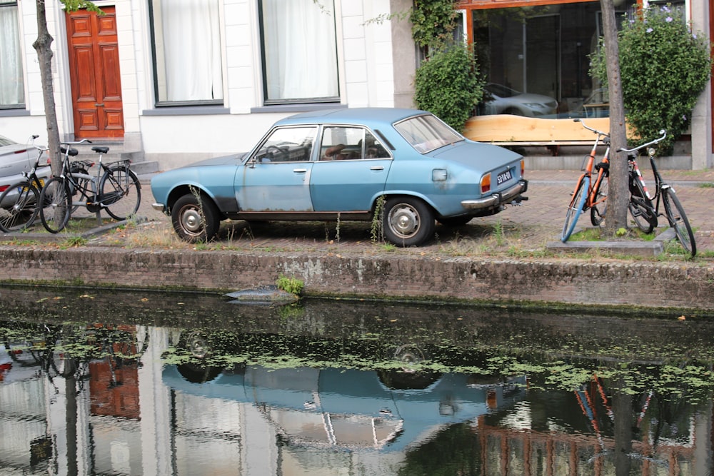 a blue car parked next to a body of water