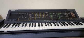 An electronic keyboard with a wide range of control buttons and features. The keys are black and white, typical of a piano, and the upper section contains numerous labels and switches for different sound settings.