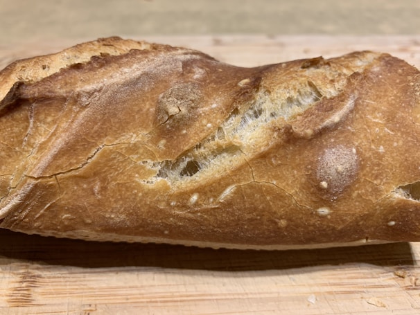 Close-up of a golden crusted sourdough loaf resting on a rustic wooden board.