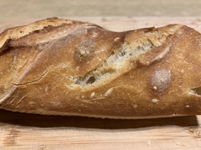 Close-up of a crusty artisan loaf with a golden-brown finish resting on a wooden board.