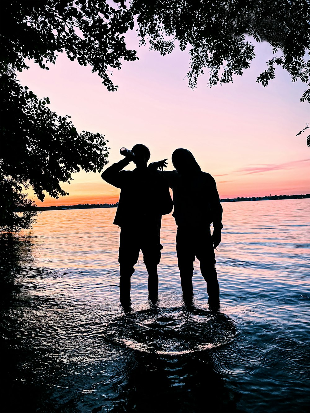 a couple of people standing on a rock in the water